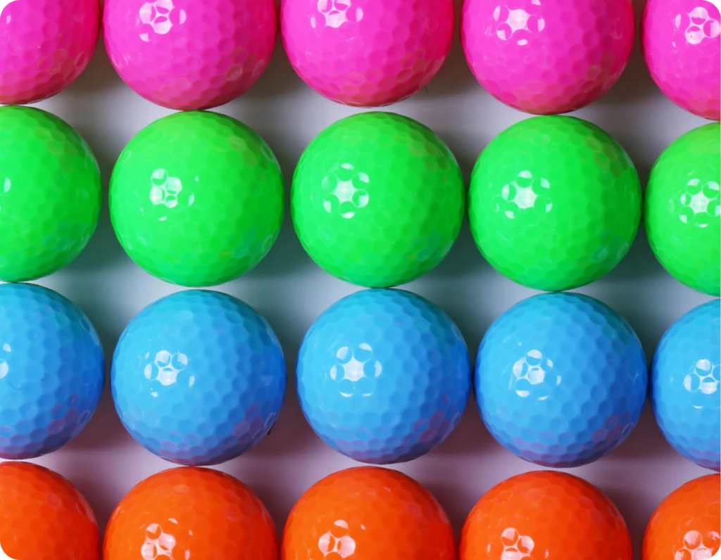 Mini golf balls arranged next to eachother in purple, green, blue and red